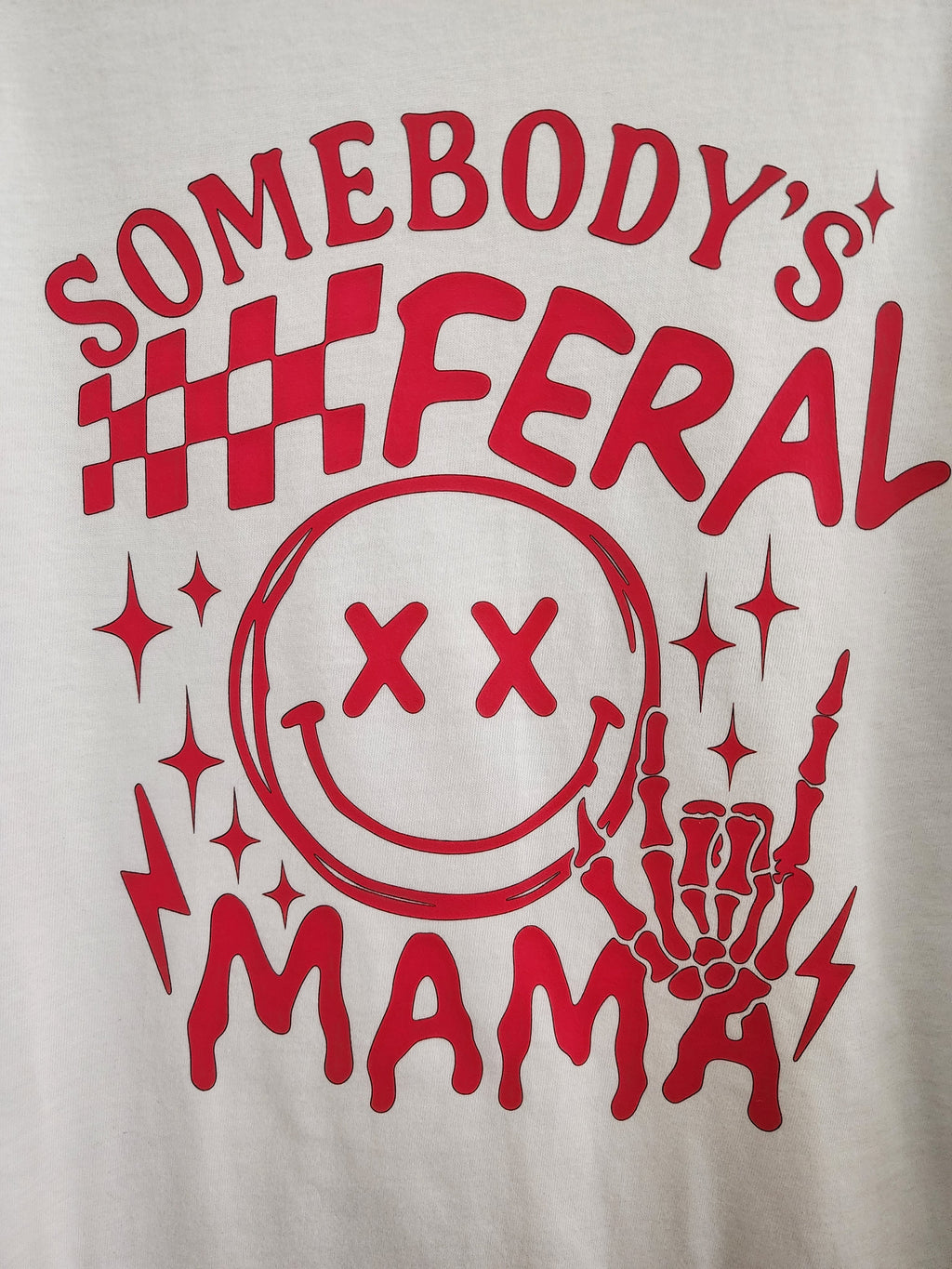 Somebody's Feral Mama DTF print close-up - red checkered flags, XX smiley and skeleton hand